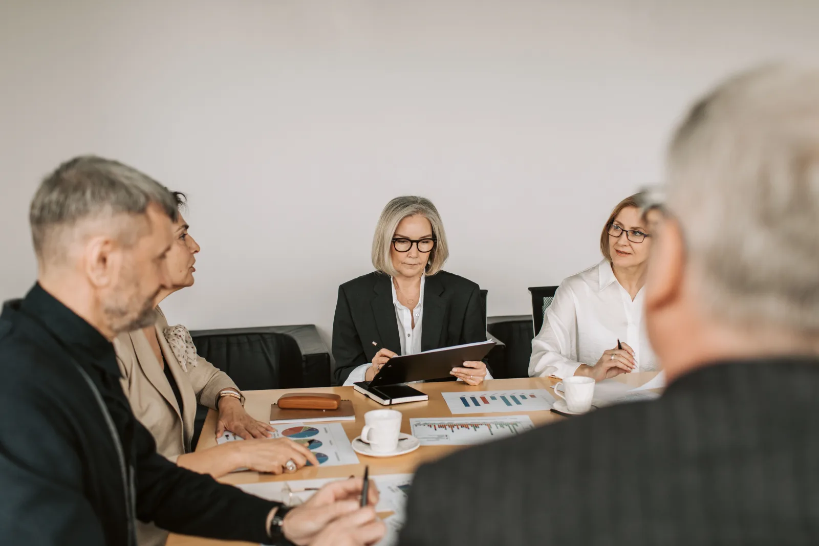Senior professionals reviewing business documents around a table