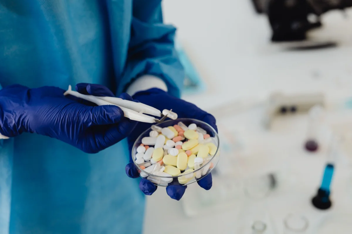 Gloved pharmaceutical safety specialist reviewing a range of medication samples