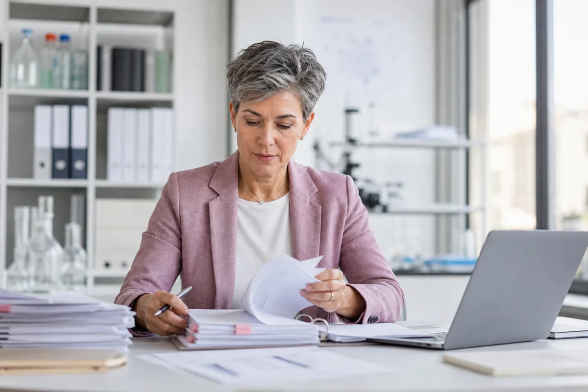 Experienced regulatory affairs consultant reviewing submission documents in a biotech office